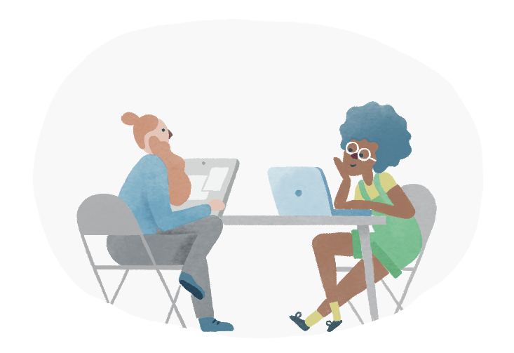 Two women working at laptops side by side at a shared table, learning together.